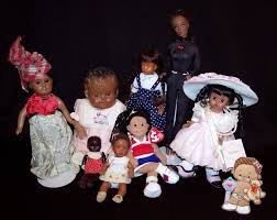 Winter is a black doll with textured braided hair, wearing a felted blue coat, a plaid wool scarf and red print skirt. Black Doll Wikipedia