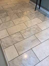 Dark grout also works nicely in homes with an emphasis on black and white. White And Gray Marble With Dark Gray Grout Grey Floor Tiles White Tile Floor Gray Shower Tile