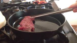 cooking venison strip in a cast iron