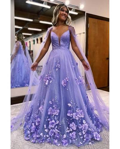 This dress understood the assignment! 💜✨ Elevate your prom night with our  stunning Lavender 3D Floral Lace A-Line Prom Dress adorned with delicate  cape sleeves. 💃🌸 Feel the luxury of exquisite lace