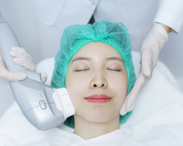 A clinician applying a skin-tightening device to a patient’s cheek