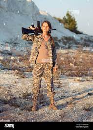 Young beautiful female soldier dressed in a camouflage with a gun in the  location Stock Photo - Alamy