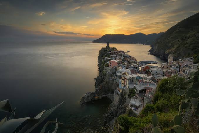 Cliffside Coastal Village at Sunset, AI generated