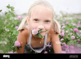 Portrait of smiling girl with clover flower in her mouth Stock Photo