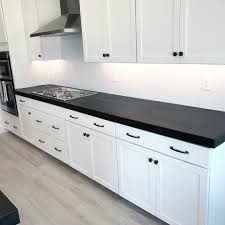 A ceiling fan cools an outdoor kitchen featuring white woven leather counter stools placed at an island clad in bedrosians enchante porcelain tiles and finished with a poured concrete countertop. 2 5 Countertop Edge On This Black Concrete Countertop The Black White Wood Floors White Concrete Countertops Concrete Countertops Countertops