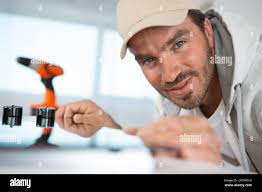 Male Repairman Installing Induction Cooker With Woman Standing In Kitchen  Stock Photo