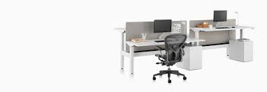 A Nevi Link Standing Desk System With A Black Aeron Office Chair Privacy Screens Monitors And Rectangular Work Surfaces Desk Aeron Office Chair Sit To Stand