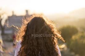 If your hair is too short in the back and sides to pull into a bun (like style number 1), you can braid or twist the front towards a pineapple, or simply leave the back and sides loose. Back View Of Young Woman With Long Curly Hair At Sunset Brown Hair Building Stock Photo 258939948