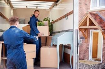 Movers unloading and positioning furniture inside a new Mauritian home