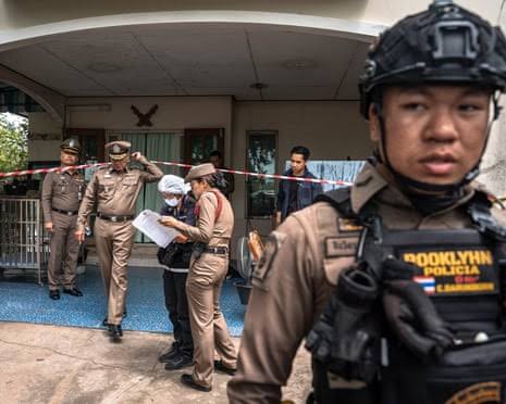 Thai police officers and emergency responders at the scene of a government building following a fatal shooting incident.