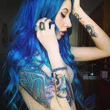 Young blue haired girl in a blue short dress and jeans with a big tattoo on her arm standing on the floor for black background. So Much Blue D Blue Hair Hair Styles Hair Tattoos