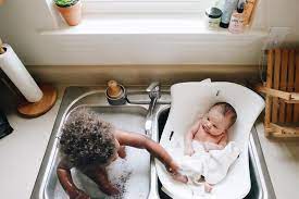 Line a sink or baby bathtub with a towel, and fill it about 2 inches full of warm water (around 100 degrees fahrenheit)—test it with your elbow or the inside of your wrist to make sure it's not too hot How To Give Baby A Bath