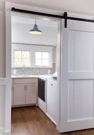 Black And White Barn Door White Cottage Laundry Room Enclosed With A Sliding White Wood Barn Door On Black Rails Kitchen Barn Doors Wood Barn Door Laundry Room Update