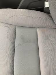 A close-up view of a different light gray fabric car seat, also showing circular water stain marks.