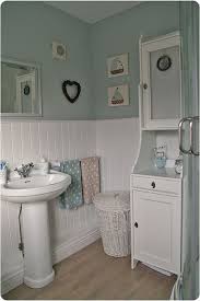In true coastal window style, this round mirror looks beautiful in this modern coastal bathroom with muted blue wainscoting and a large white bathtub for soaking. Evolyuciya Sanuzla Cottage Style Bathrooms Cottage Bathroom Cottage Bathroom Design Ideas