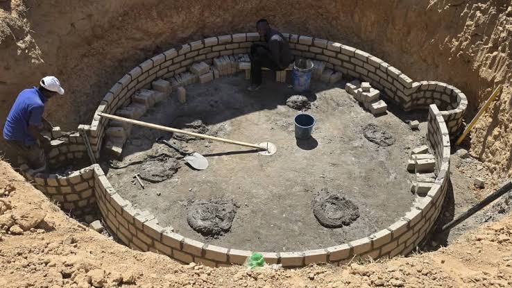 Local African youth constructing a brick biogas digester