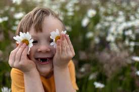 Girl covering eyes with daisy flower in field stock photo