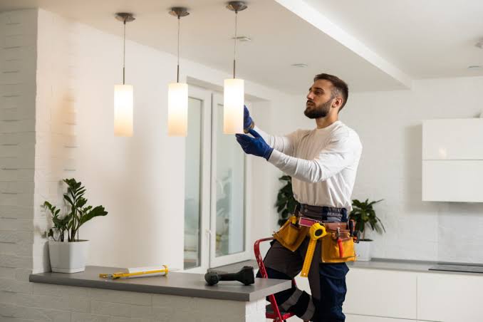 Professional fitter installing a ceiling fan and downlights in Swanley