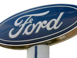 A blue work from home logo represented by a person at home in front of their computer with a wifi signal. Ford Is The First Automaker To Allow Permanent Working From Home