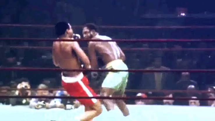 Frazier derribando a Ali con su golpe firma., generada por IA