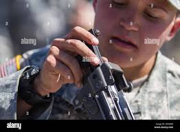 Specialist Mariah Madaras, a member of the Headquarters Headquarters  Company, 158th Maneuver Enhancement Brigade, attempts to slide the bolt  carrier assembly of a M249 Squad Automatic Weapon back in to position before