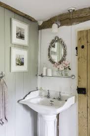 Cottage bathroom with a pocket door is designed with a faded vintage runner atop light oak plank floors between a white vanity and a freestanding tub next to a walk in shower. Real Home A Tiny Thatched Cottage Full Of Light Cottage Style Bathrooms Cottage Bathroom Bathrooms Remodel
