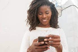 Happy Focused Black Girl Chatting Online On Mobile Phone. Young Woman In  Casual Using Smartphone Outdoors And Smiling At Screen. Online Chat Concept  Stock Photo, Picture And Royalty Free Image. Image 124600923.