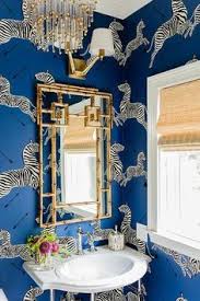 Playful scalamandre zebra wallpaper graces the walls of this well designed kid bathroom featuring a west elm metal framed hexagon mirror flanked by architectural wall sconces mounted above a white washstand fitted with brushed brass knobs, a white countertop, and a round sink with a gold faucet. Chinoiserie Chic Zebra Wallpaper Scalamandre Zebra Wallpaper Home