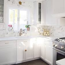 This kitchen features traditional white shaker cabinets with a beige and brown stone splash. White Shaker Cabinets With White Marble Subway Tiles Transitional Kitchen