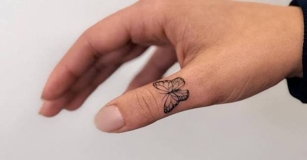 Tiny butterfly tattoo located on the thumb.