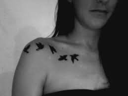 A black bird silhouette is portrayed next to an open cage in this tattoo rendered on the wearer's right shoulder blade. 41 Collar Bone Birds Tattoos