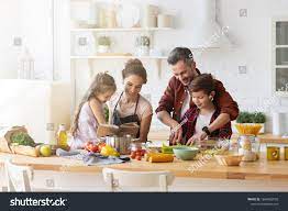 Happy Family Cooking Together On Kitchen Mother And Daughter Reading Recipe To Father And Son Dad And Boy Ch Family Cooking Cooking Together Green Vegetables