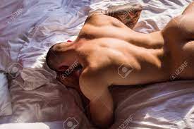Handsome Nude Man Lying In A Bed. Top View Of Handsome Young Man In Bed In  Bedroom At Night. Muscular Handsome Man Laying On Stomach In Bed. Guy Lying  On Belly And