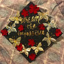 Roll up the paper and tie the red ribbon bow to make the diploma. Graduation Cap Ideas Dream The Impossible Red Flowers With Gold Butterflies College Graduation Cap Decoration Graduation Cap Decoration Flower Graduation Cap