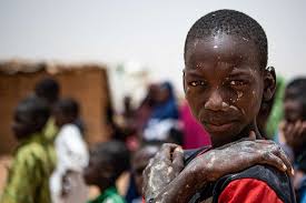 Dirt covers the face and arms of a Nigerien boy at