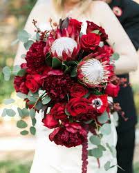 Green hydrangea blossoms act as a neutral buffer between the intense colors of the other flowers. Red Protea Red Peony Red Rose Wedding Bouquet Designed By Tricia Cfd Red Bouquet Wedding Peonies Wedding Centerpieces Wedding Bouquets