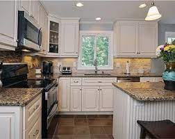 However, the soaring walls are white which gives white cabinets contrasted with black countertops and black appliances and then all tied together with a metallic blue backsplash. Kitchen White Cabinets Black Appliances Ideas