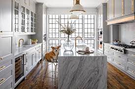 The light gray cabinetry contrasts well with the white island, marble countertops and subway tile. Gray And Gold Kitchen Design Transitional Kitchen
