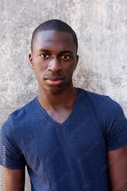 Handsome young black guy standing agaisnt gray wall Stock Photo