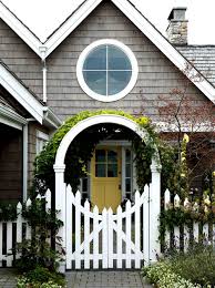 Points of interest ● wood white pickets on concrete fence ● pale yellow thin siding ● covered balcony above porch ● green shutters ● palm trees in points of interest ● flowering plants in varying heights ● regular point white washed wooden picket fence ● lavender colored blooms with yellow wildflowers. 12 Charming Picket Fence Ideas Town Country Living