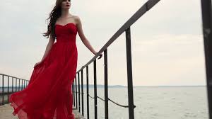 But you know what gets me through the days? Brunette Wearing Red Chiffon Dress Is Standing On A Quay In Cloudy Summer Day Wind Is Swaying Her Skirt Woman Is Looking In A Distance Camera Is Moving Stock Video Footage