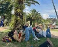 Image of student studying in a park with palm trees in the background