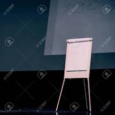 Podium Of The Seminar With A Flip Chart And A Large Screen