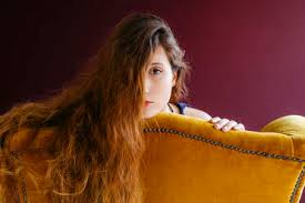 Tortoiseshell brown hair with honey blonde highlights. Close Up Portrait Of Young Woman With Long Brown Hair Leaning On Golden Chair Against Colored Background Stockphoto