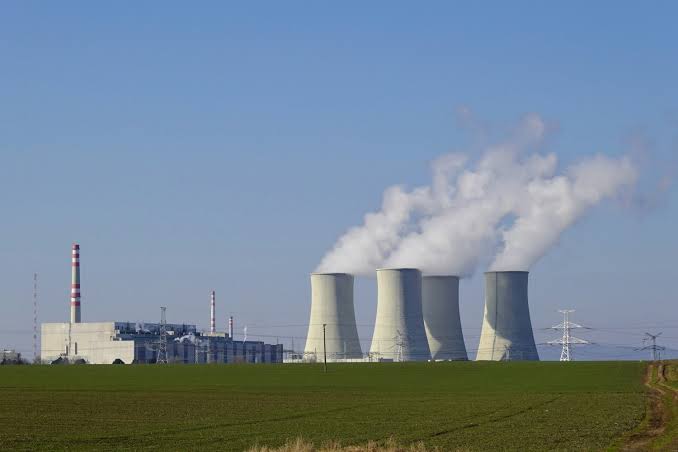 Aerial view of a nuclear power plant cooling tower emitting steam during a summer heatwave in Europe.
