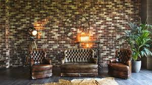 The layered rugs on the floor lend visual texture and bold color. Bachelor Pad Exposed Brick Fireplace Chesterfield Sofa Dark Brown Sofa Decorating Ideas Mid Century Stock Photo Image Of Real Lamp 158040718