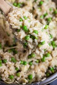 Scoop Of Cooked Cheesy Arborio Rice And Peas Lifted From Skillet In 2020 Rice Stuffing Recipes Risotto Recipes Risotto