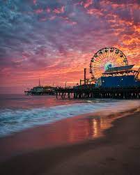 Palm trees are photomount too. A Fiery Sunset Over Santa Monica Pier Los Angeles California Photography Travel Aesthetic Los Angeles Wallpaper