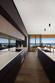 With both counters placed adjacent to each other, this layout ensures efficiency while cooking. Modern Galley Kitchen With Smokey Mirror Splashback And Black Cabinetry By Woodstock Indu Luxury Kitchen Modern Luxury Kitchens Luxury Kitchen Design