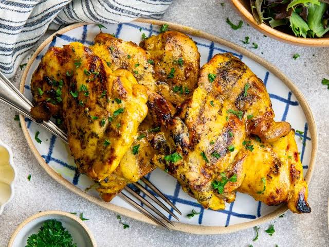 Raw chicken strips marinating in a yellow turmeric and coconut milk mixture for Thai skewers